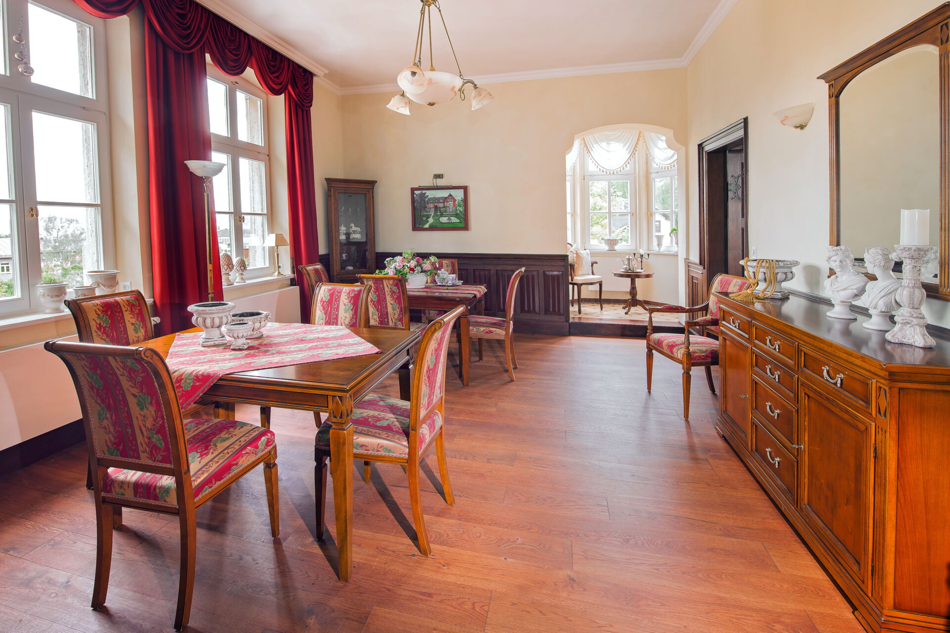Ein großes, klassisch eingerichtetes Esszimmer in einer Villa mit Holzboden und hellen Wänden.